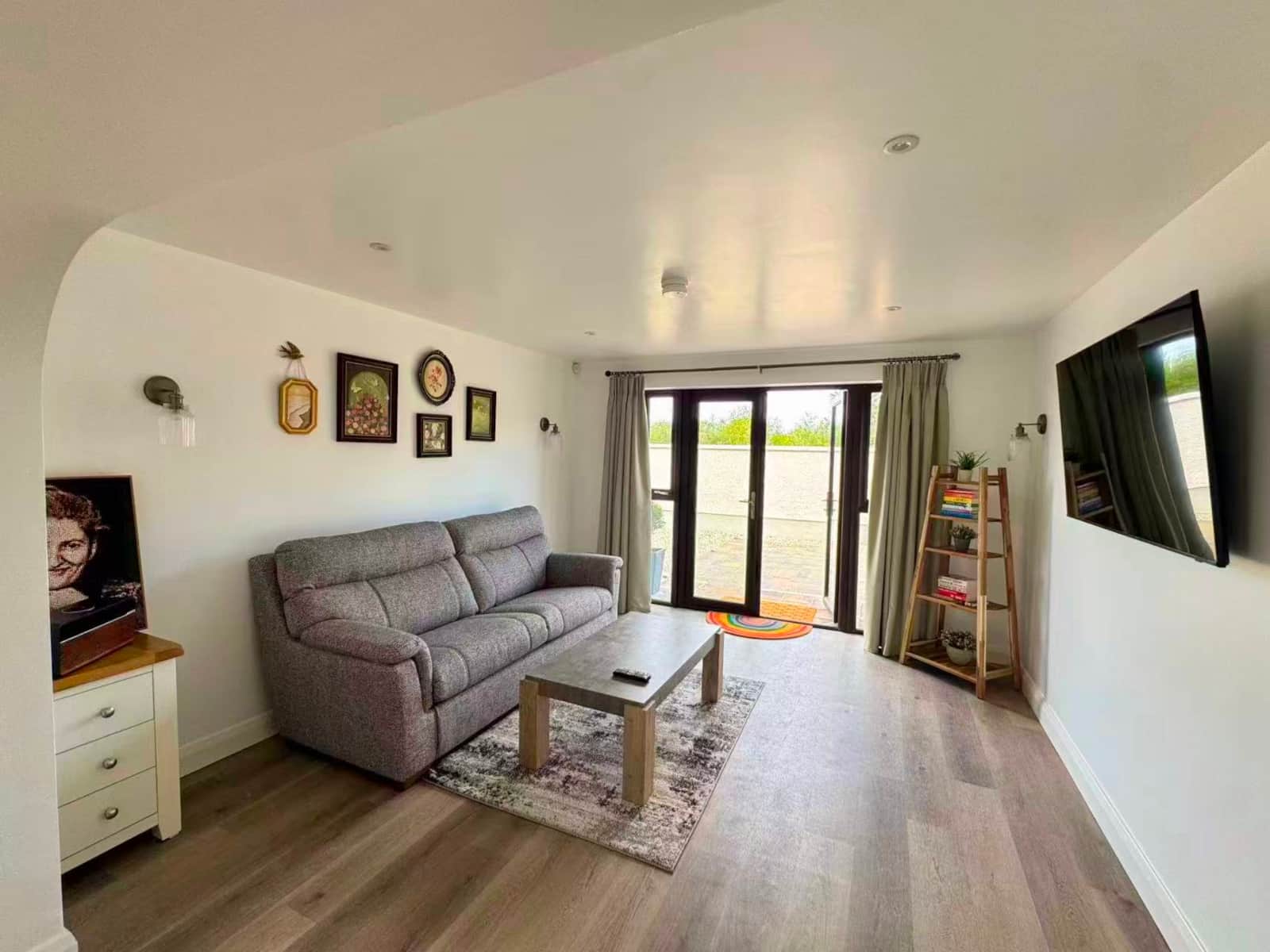 Bright sitting room with sofa, television and patio doors